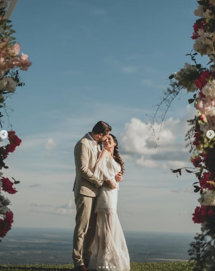 Bride and groom under floral arch with view