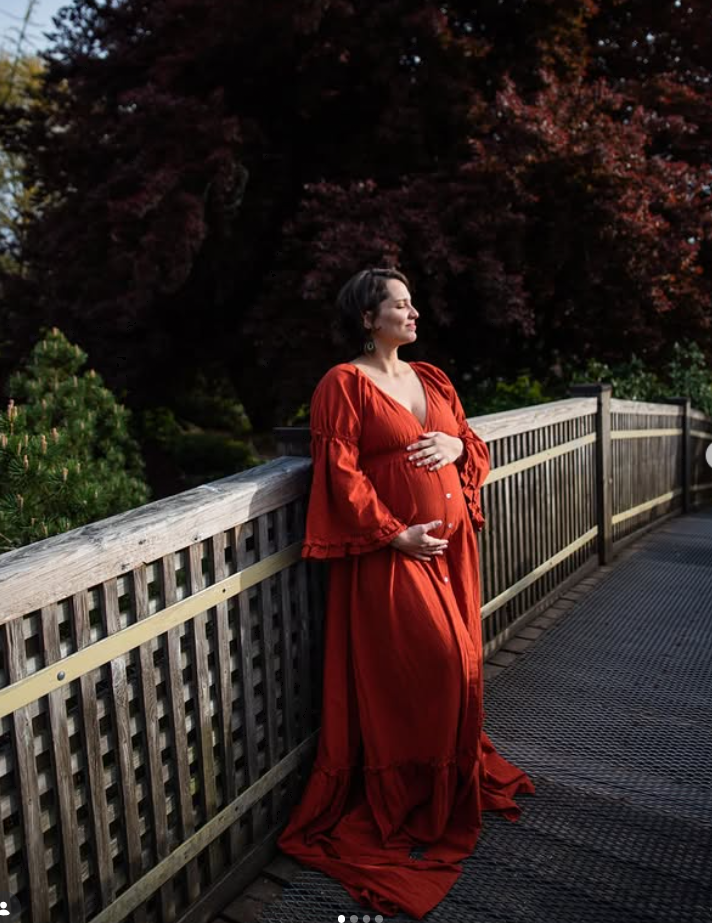 Expectant mother in a red dress on a bridge
