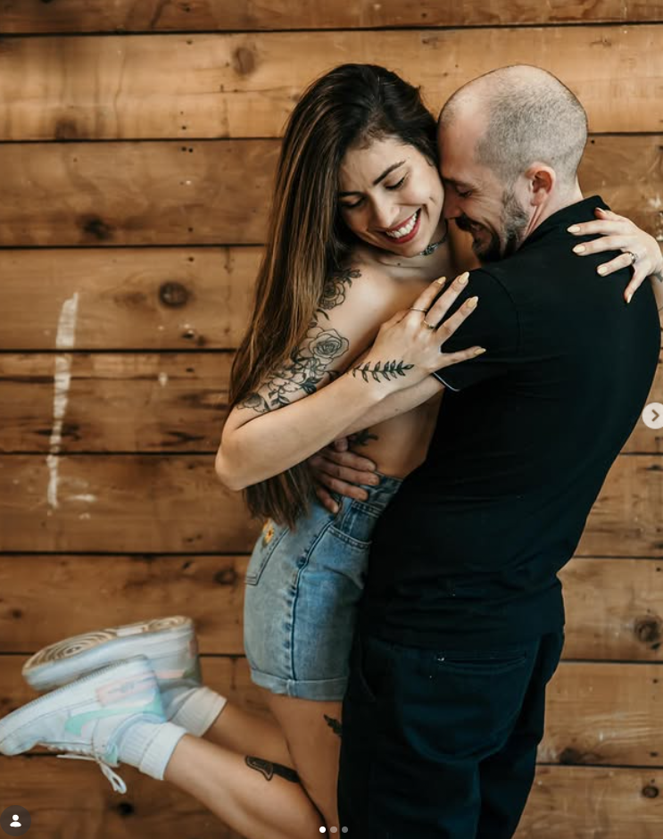 Couple embracing against a wooden wall